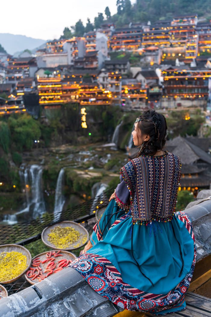 Joven sentada admirando la belleza de la ciudad en Lijiang